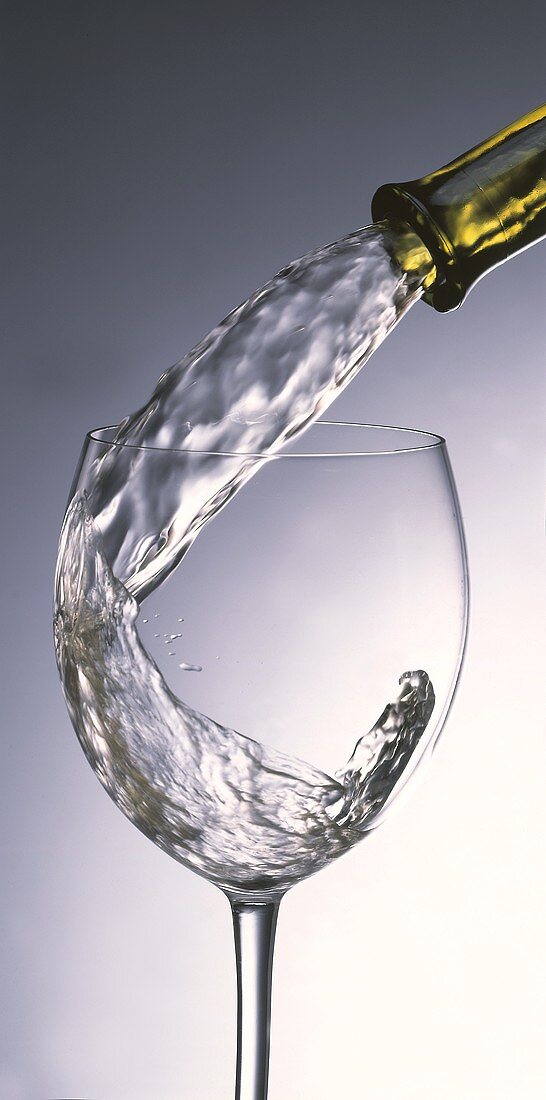 Weißwein aus der Flasche ins Glas eingiessen
