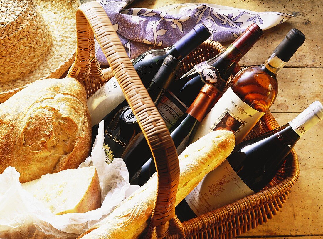 Basket with bottles of wine, hard cheese & white bread