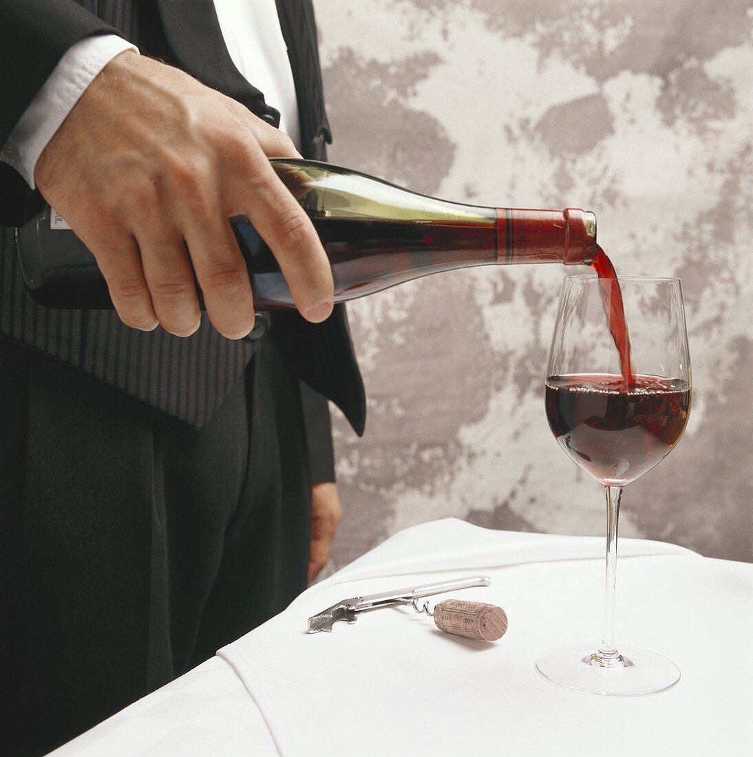 Kellner giesst Rotwein in ein Glas