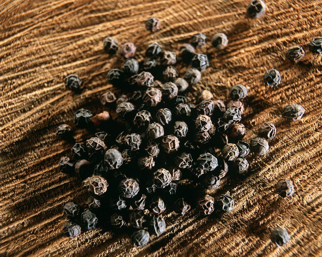 Black peppercorns on brown background