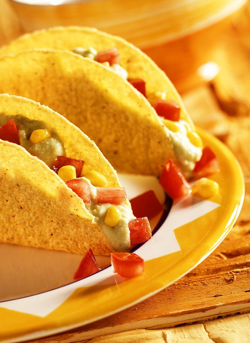 Taco-Shells mit Avocadopüree, Mais und Tomaten