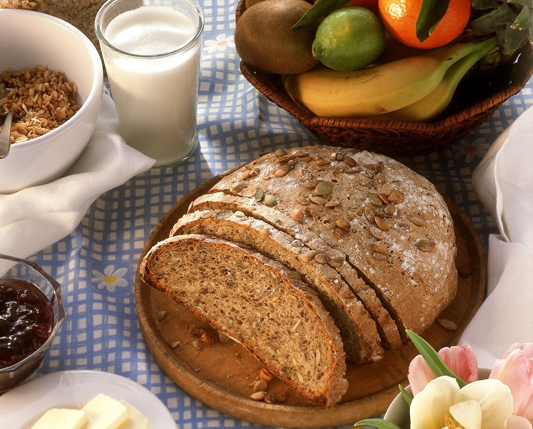 Ein Kürbiskernbrot mit Milch, Marmelade, Obst und Müsli