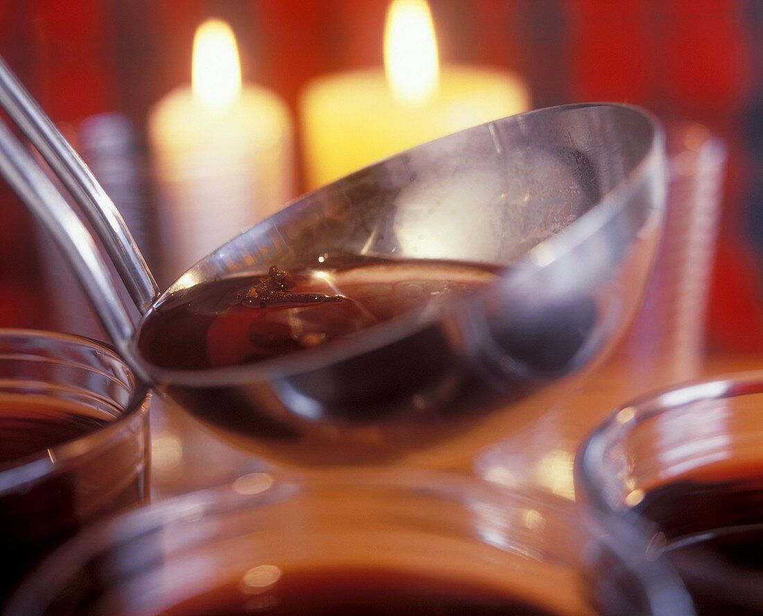 Weinpunsch in einer Kelle, Kerzen im Hintergrund