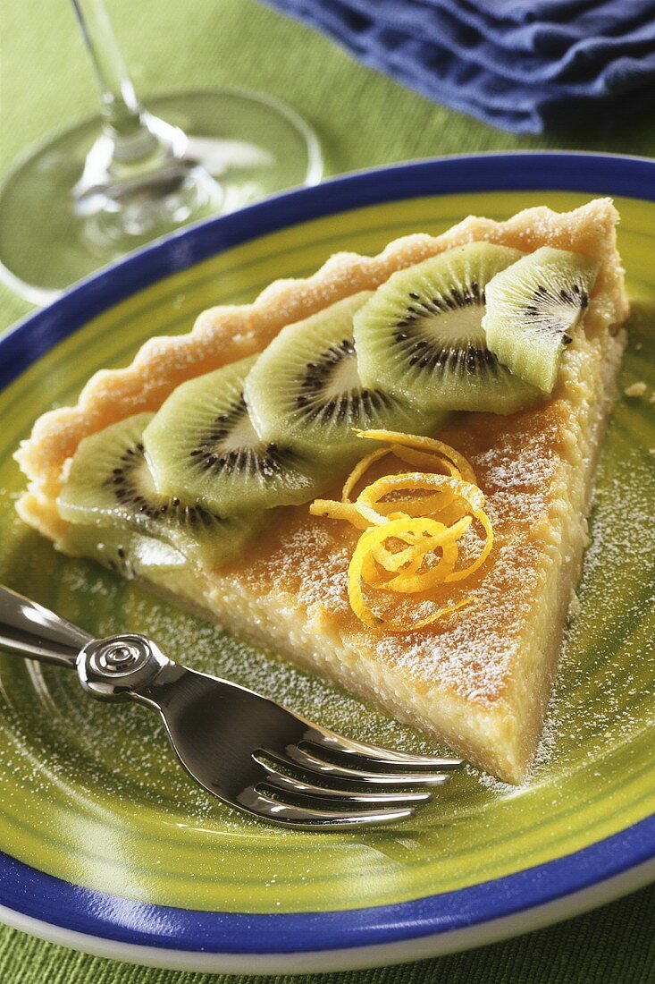 A piece of lemon & kiwi tart on dessert plate with fork