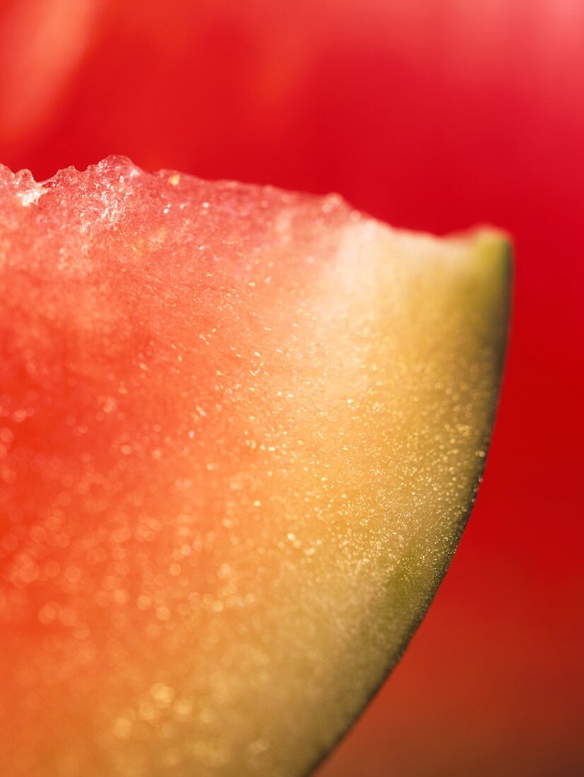Eine Scheibe Wassermelone vor rotem Hintergrund