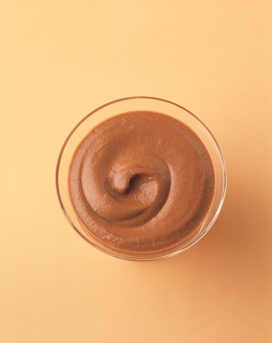 Chocolate mousse in a glass against beige backdrop