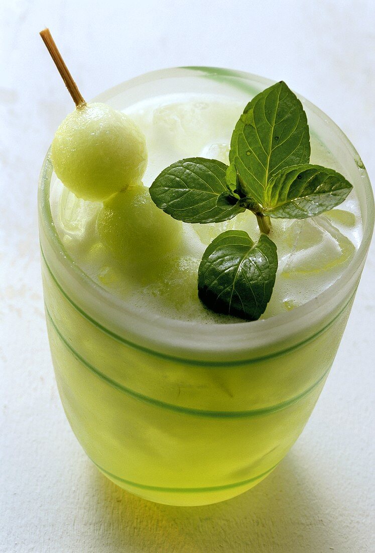 Melon drink with melon ball on cocktail stick and mint