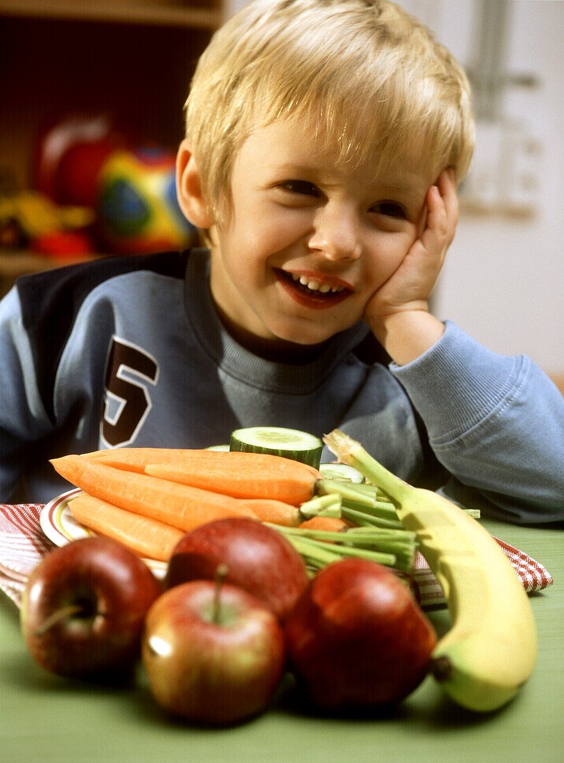 Kleiner Junge sitzt am Tisch mit Obst und Gemüse
