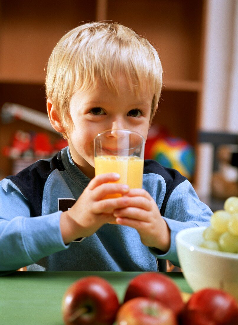 Kleiner Junge trinkt ein Glas Orangensaft
