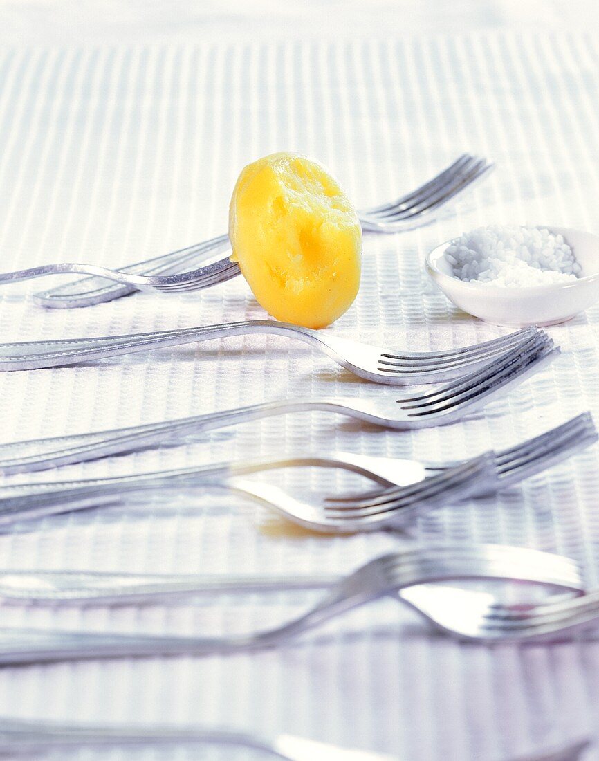 Peeled potato with coarse-grained salt and forks