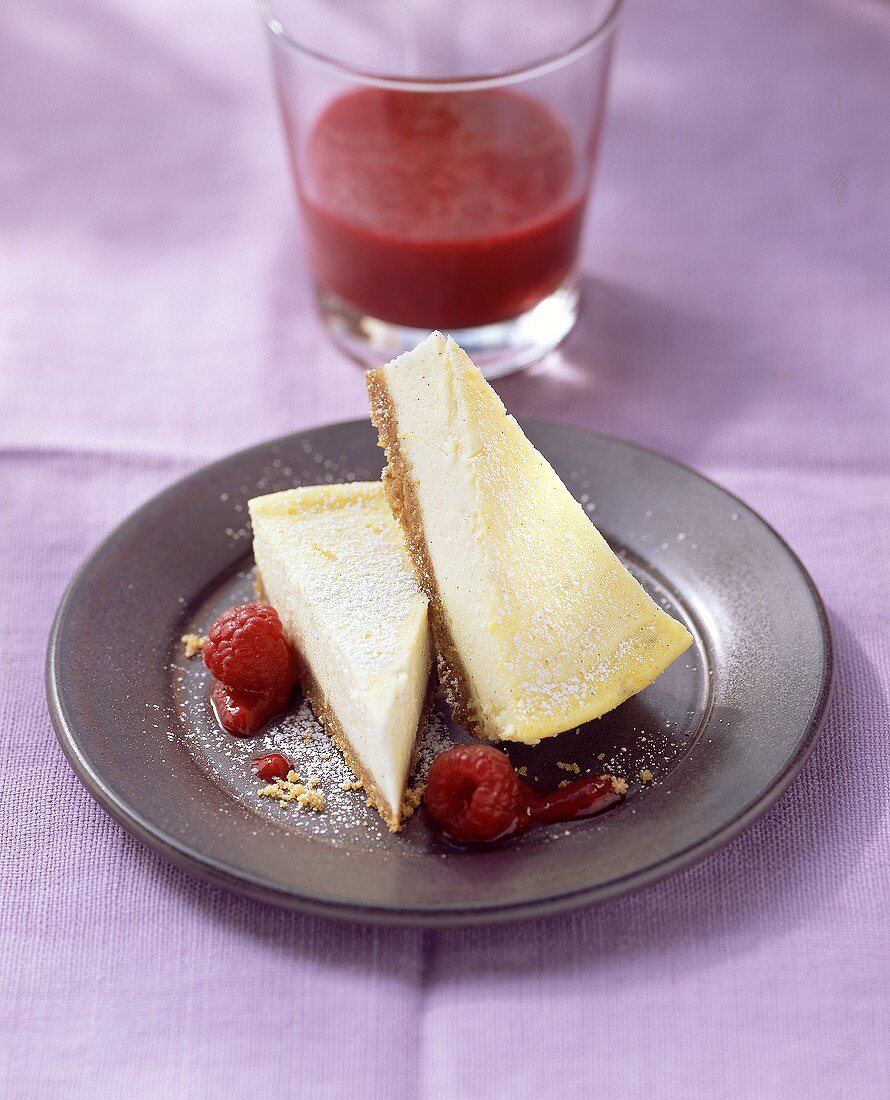 Zwei Stück Cheesecake mit Himbeersauce und Himbeeren