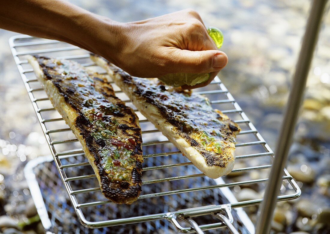 Gegrillte Fischfilets mit Zitrone beträufeln