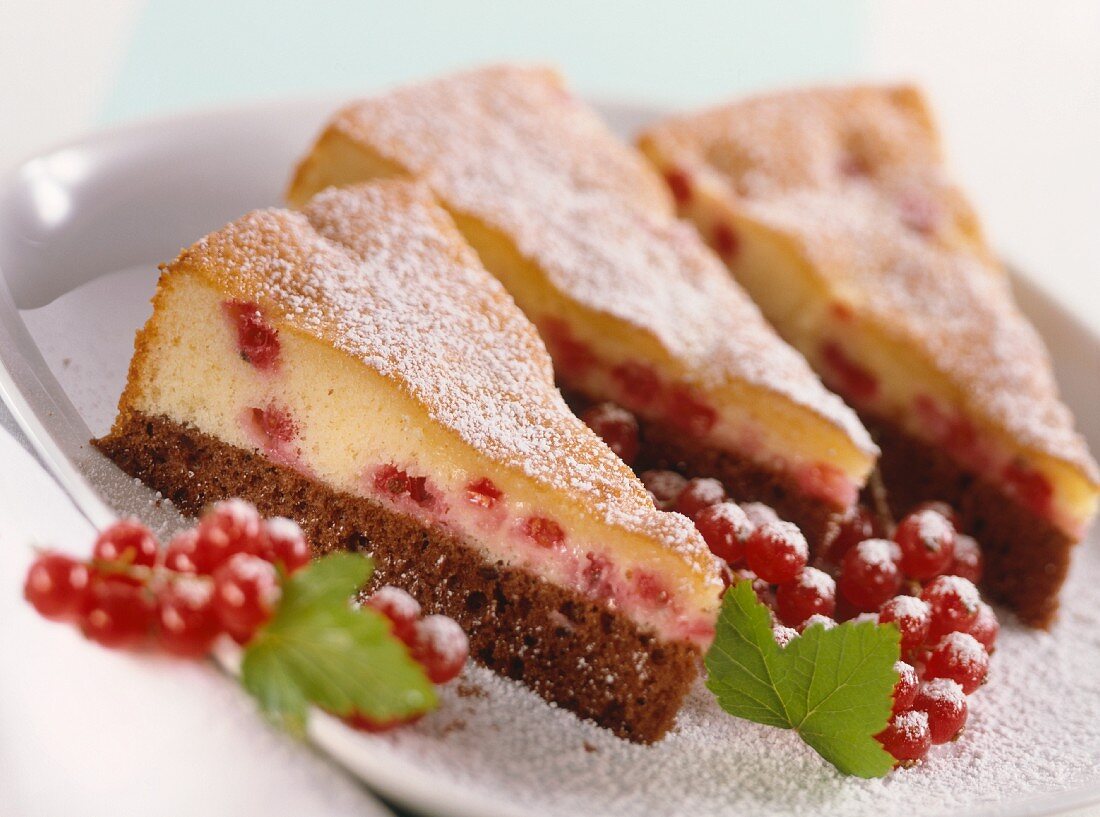 Three pieces of black and white cake with redcurrants