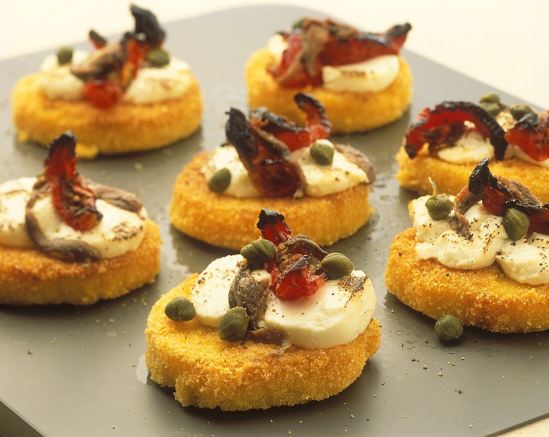 Polenta-Parmesan snacks with anchovies, capers, sheep cheese