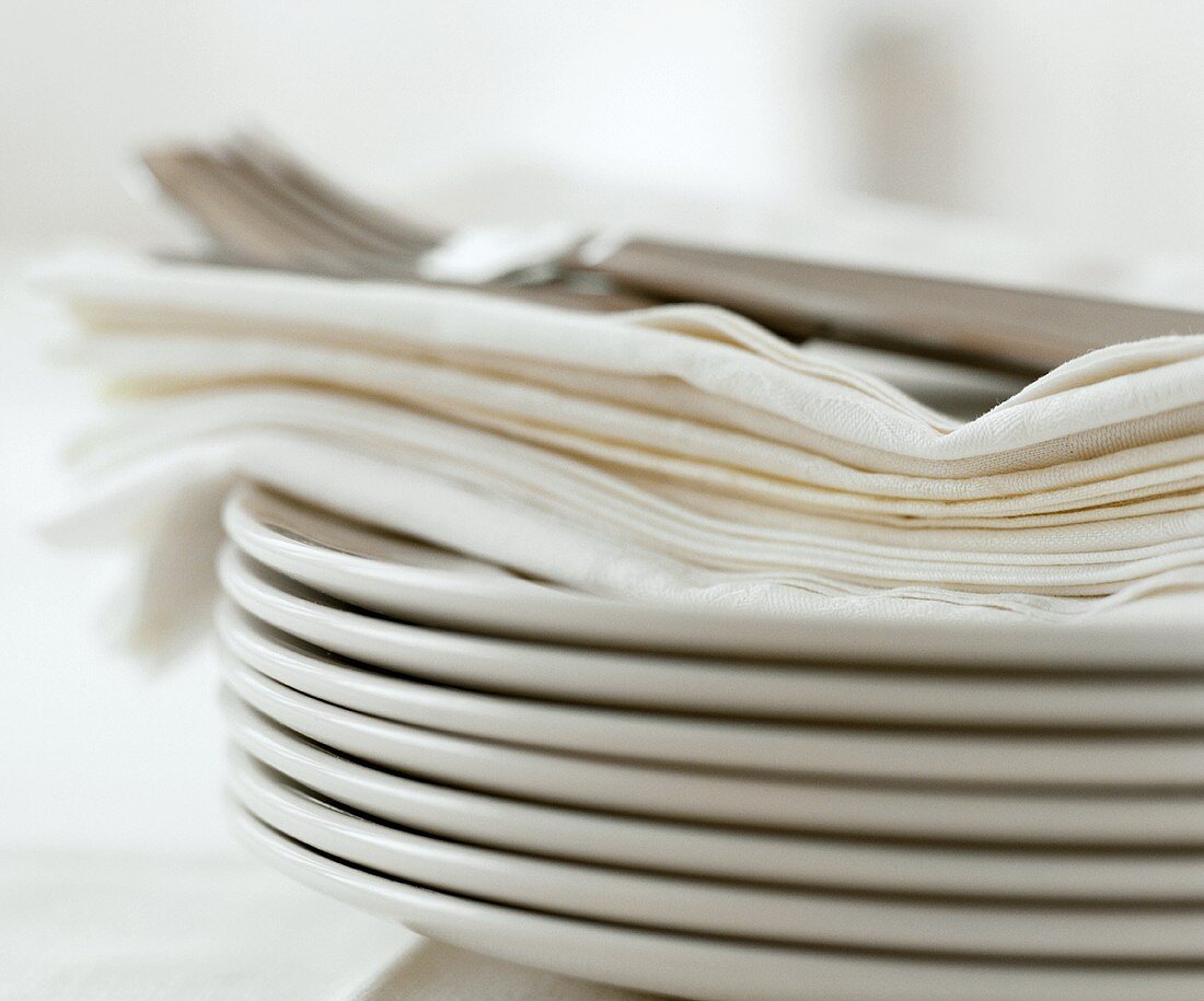 A pile of plates with napkins and cutlery