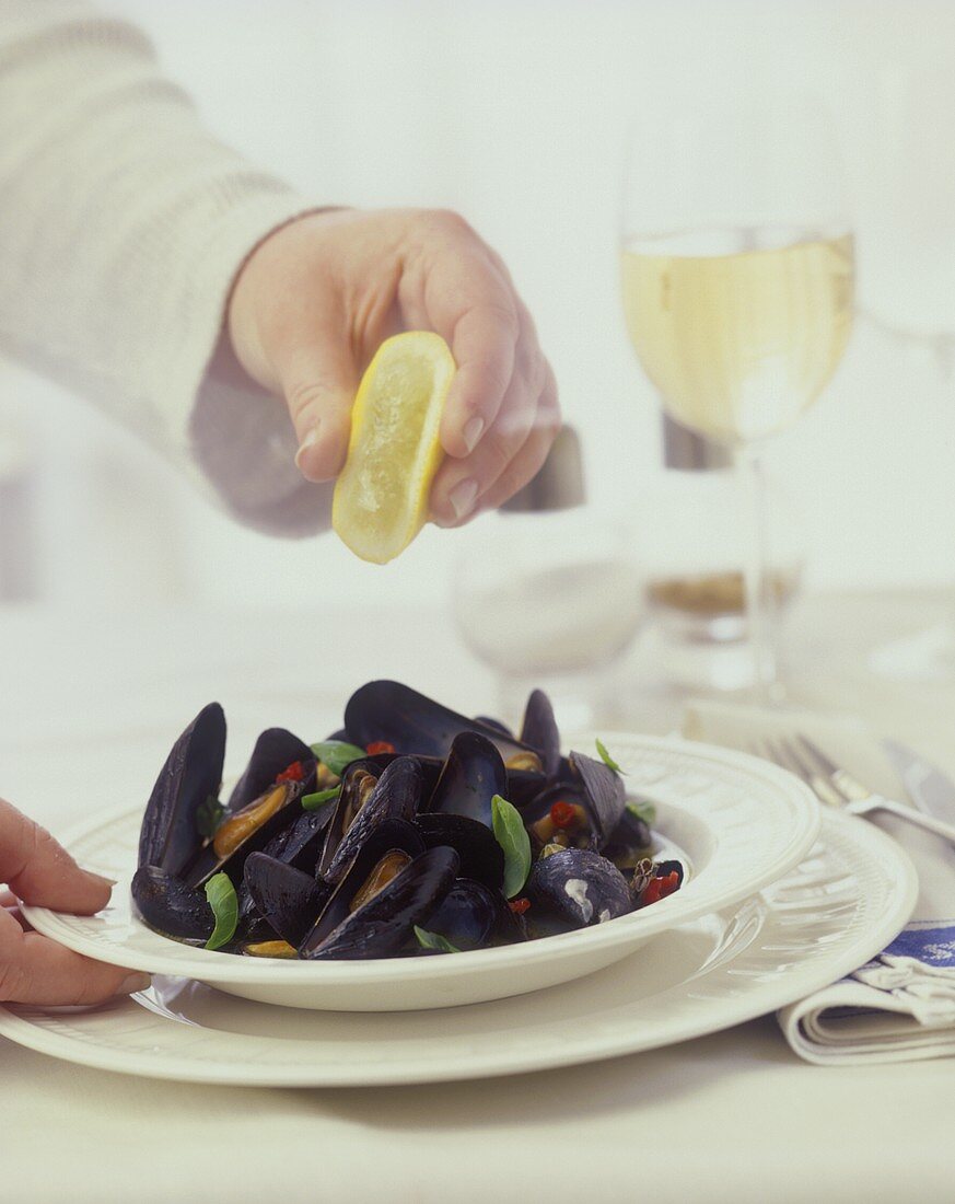 Sprinkling steamed mussels with lemon
