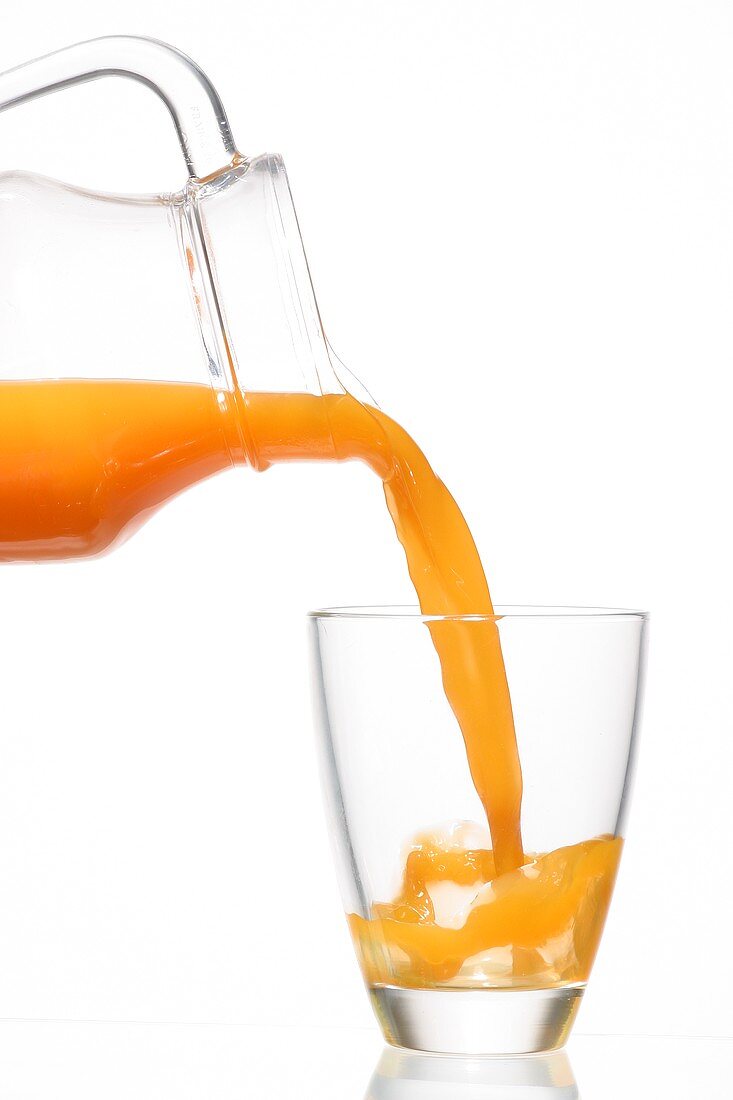 Pouring multi-vitamin juice from a carafe into a glass