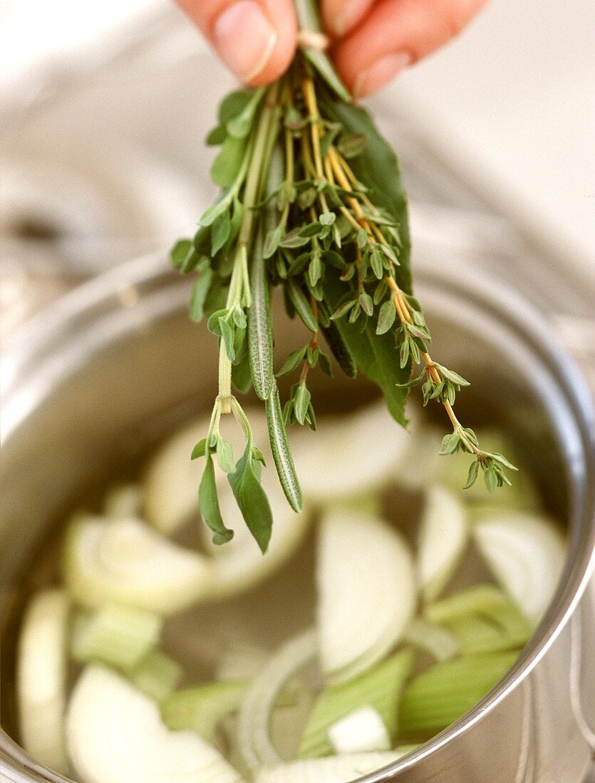 Kräuter in die Suppe geben