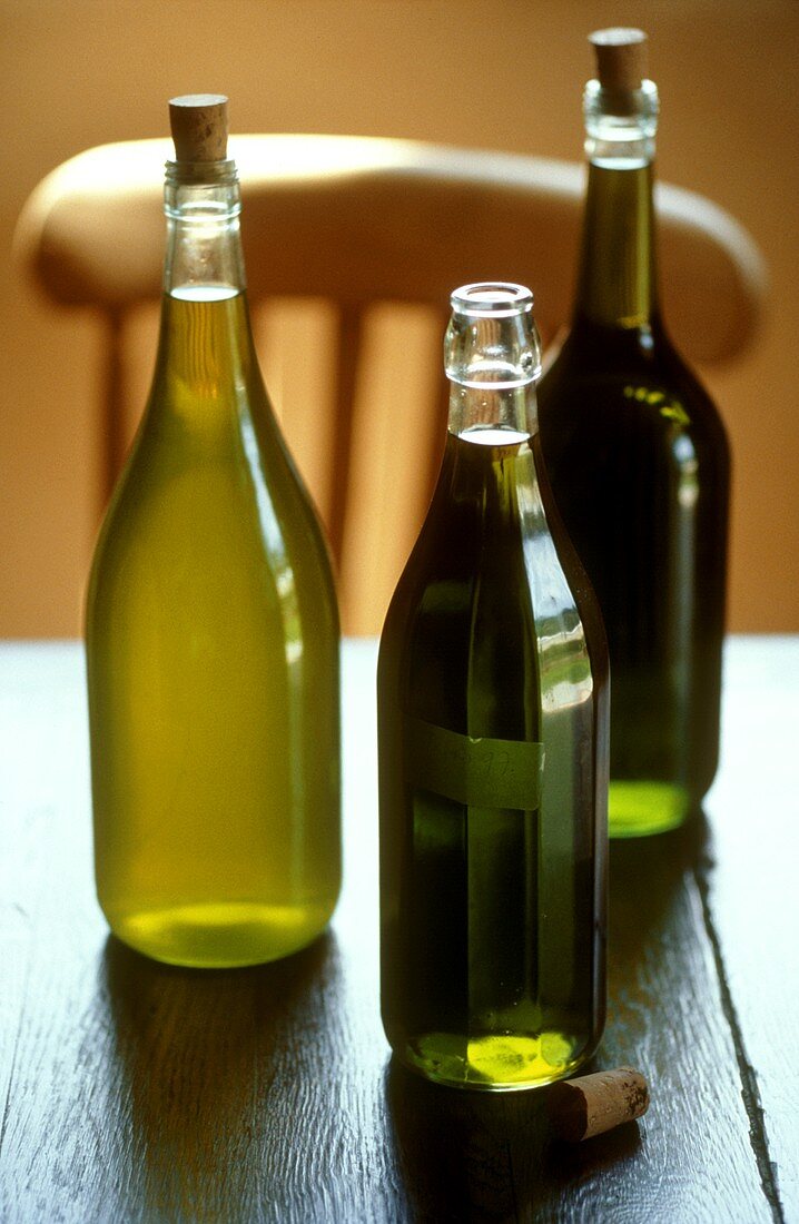 Drei verschiedene Olivenöle auf Holztisch
