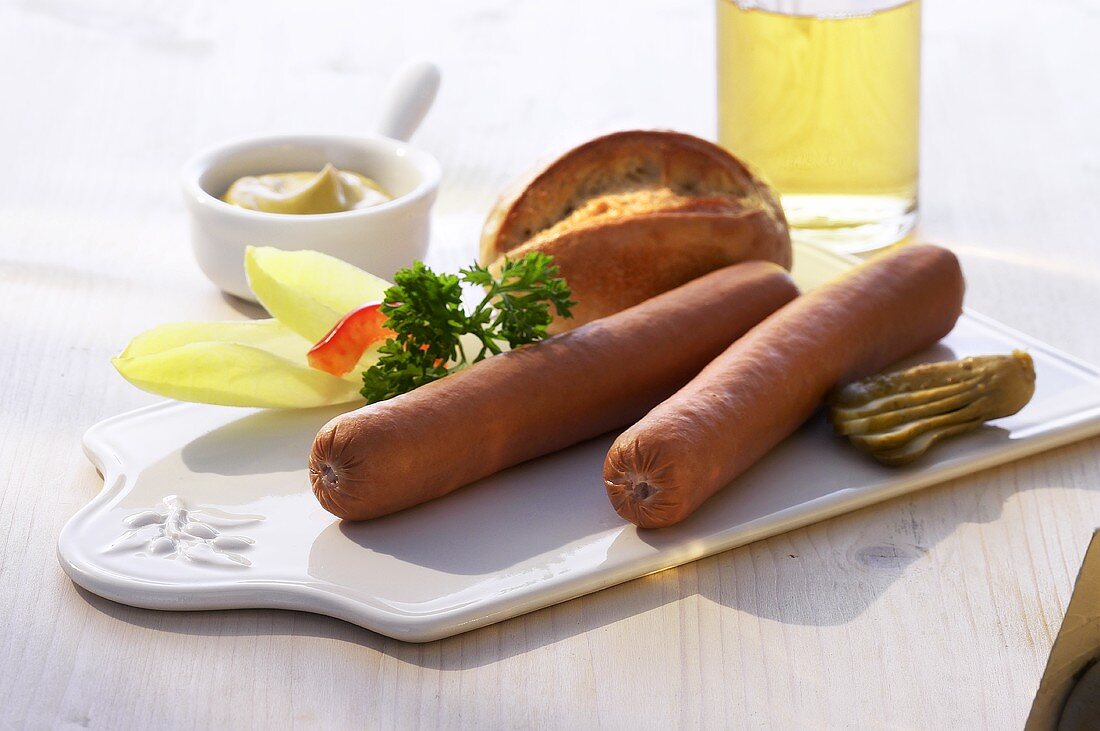 Two sausages on chopping board; lettuce garnish, roll, mustard