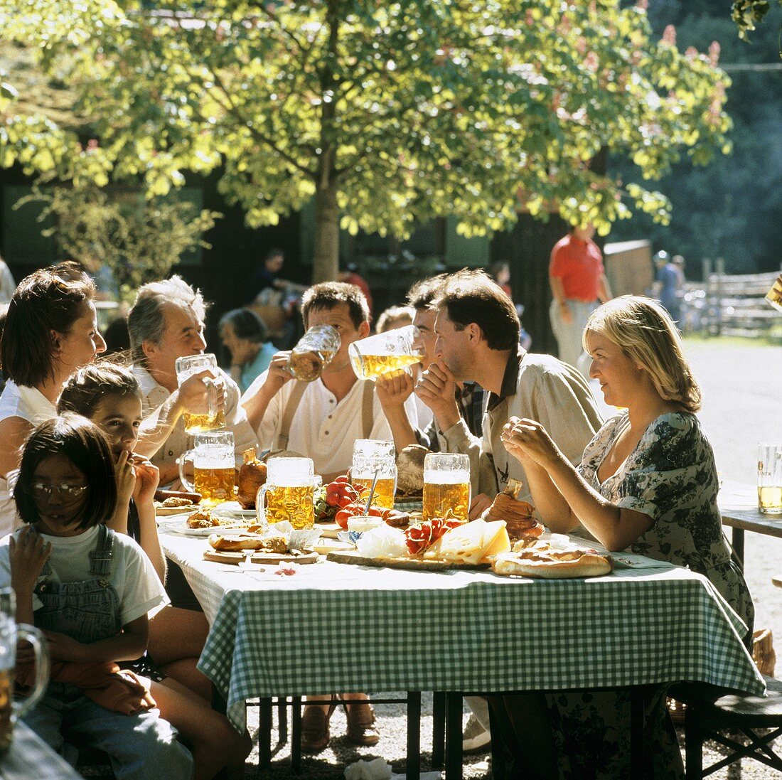 Junge Leute mit Bier & bayerischen Schmankerln im Biergarten