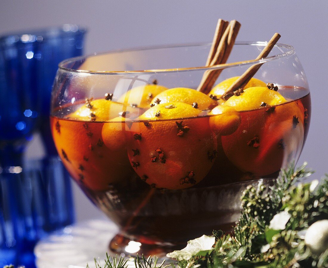 Weihnachtspunsch mit ganzen Orangen in Glasschale