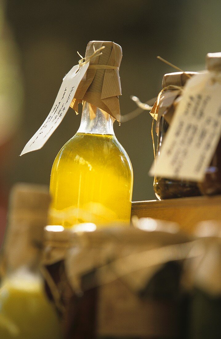 Bottle of olive oil sticking up above jars of preserves