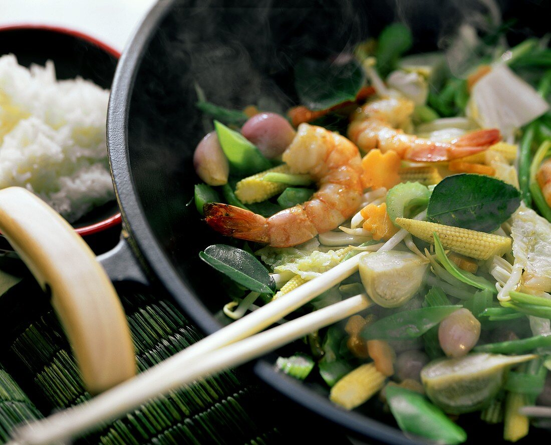 Wok mit dampfendem pfannengerührten Gemüse und Garnelen