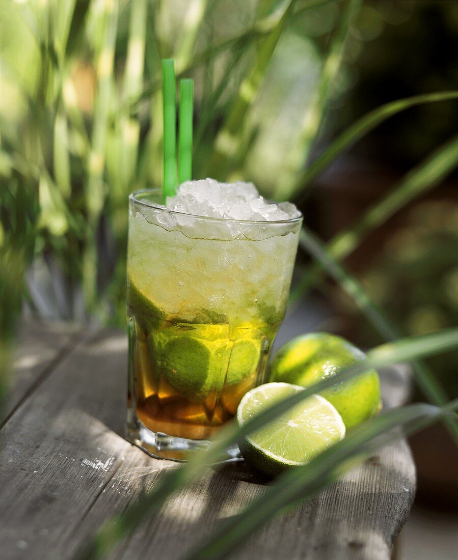 Glas Caipirinha auf einem Holztisch im Freien