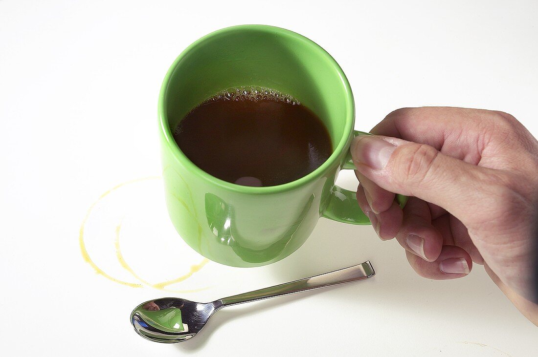 Grüne Kaffeetasse wird von einer Hand gehalten