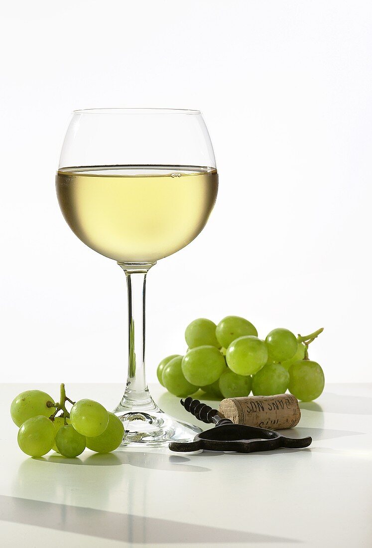 A glass of white wine with fresh grapes