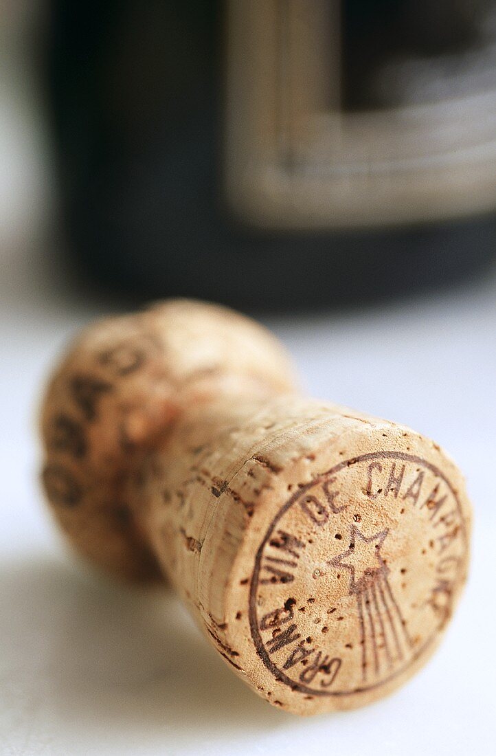 A champagne cork in front of champagne bottle