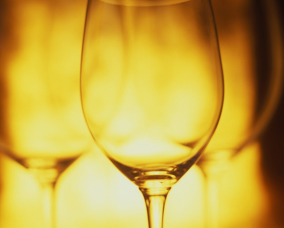 Several empty glasses side by side in yellow light