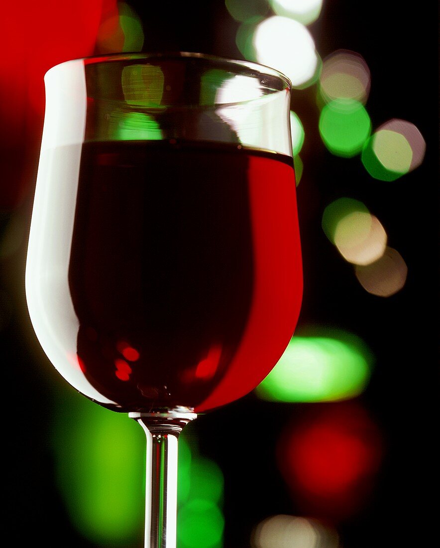 Rotwein im Glas, farbige Lichtreflexe im Hintergrund