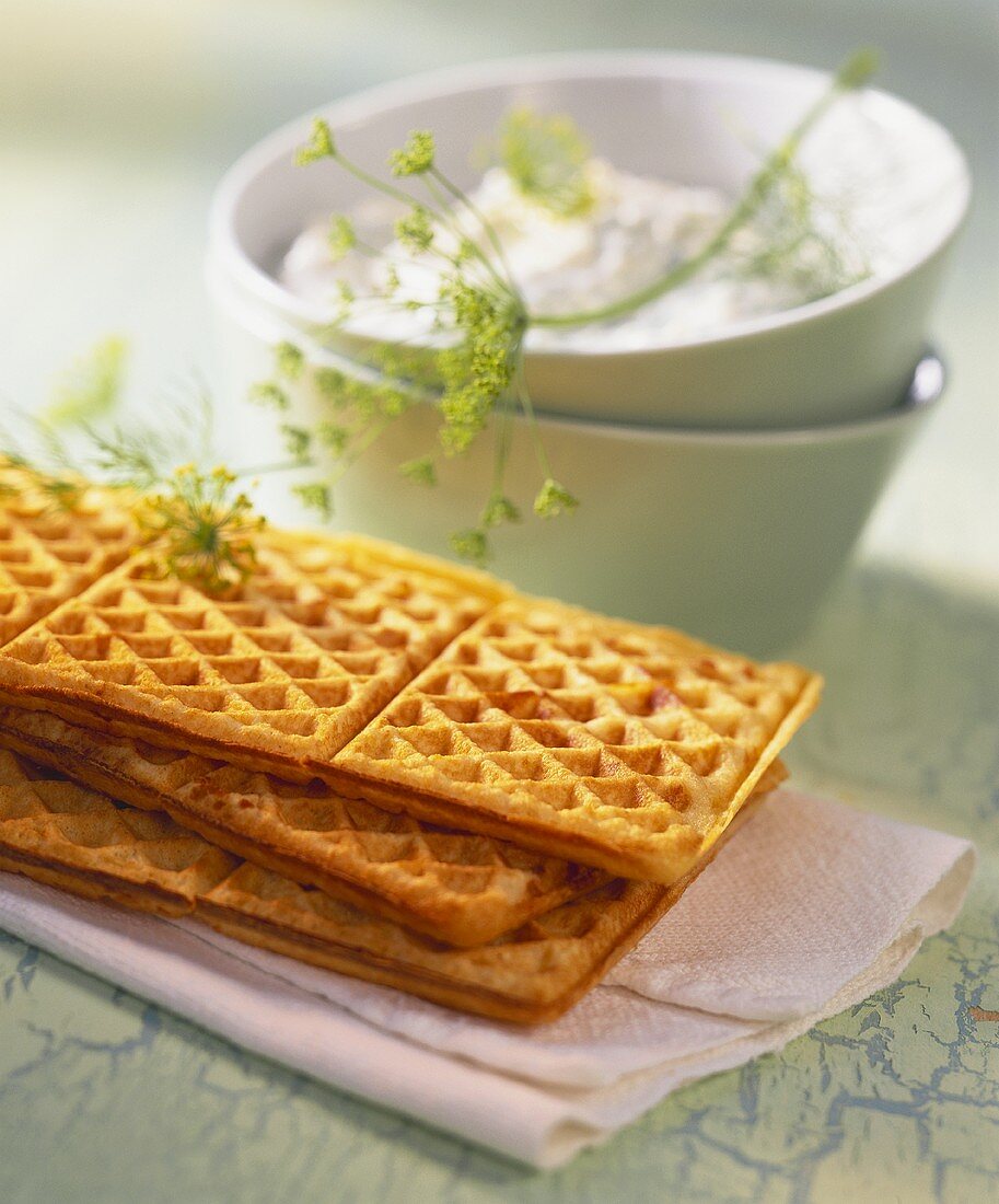 Tasty cheese waffles and a bowl of quark with dill