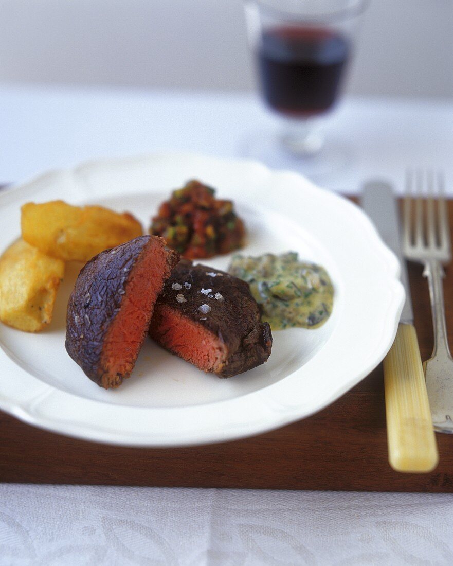 Beef steak with baked potato wedges and two sauces