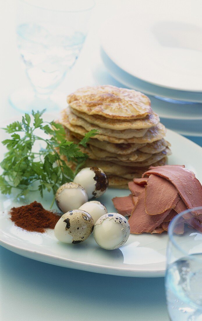 Blinis, ham and quail's eggs on a plate