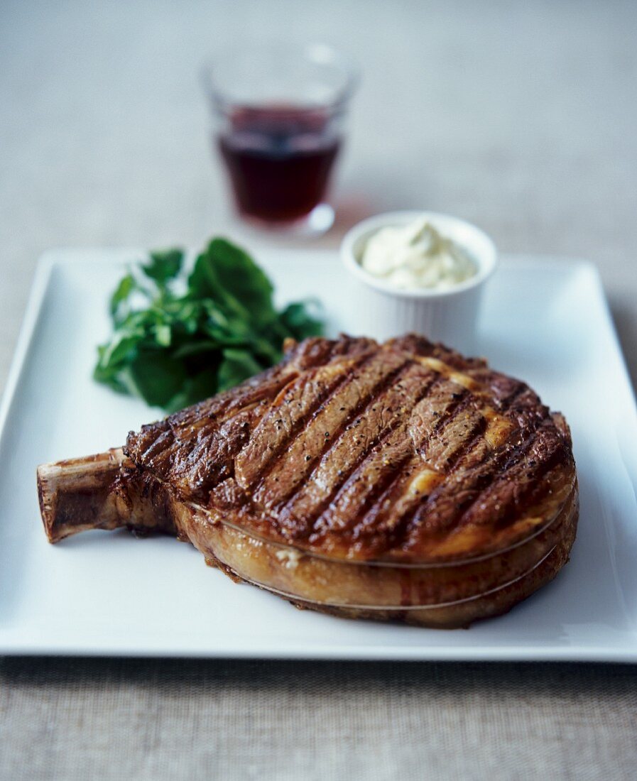 Barbecued chop, watercress and bowl of sauce