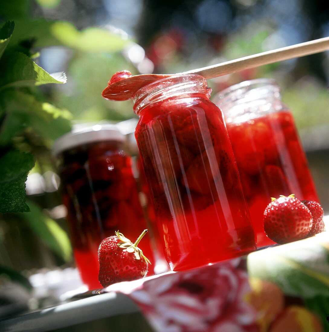 Three jars of strawberry jam on a garden table