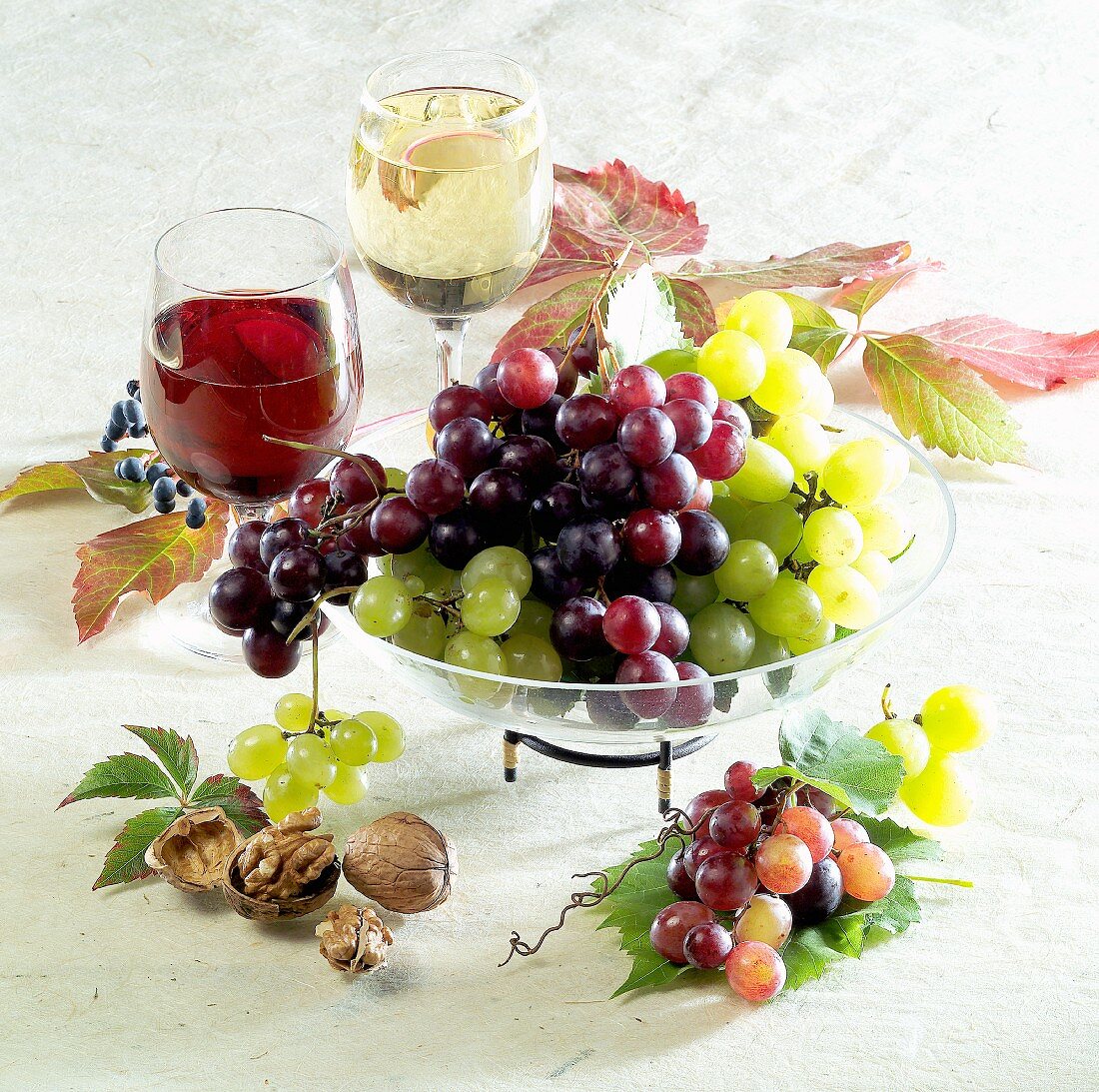 Still life with grapes, red and white wine glass, nuts