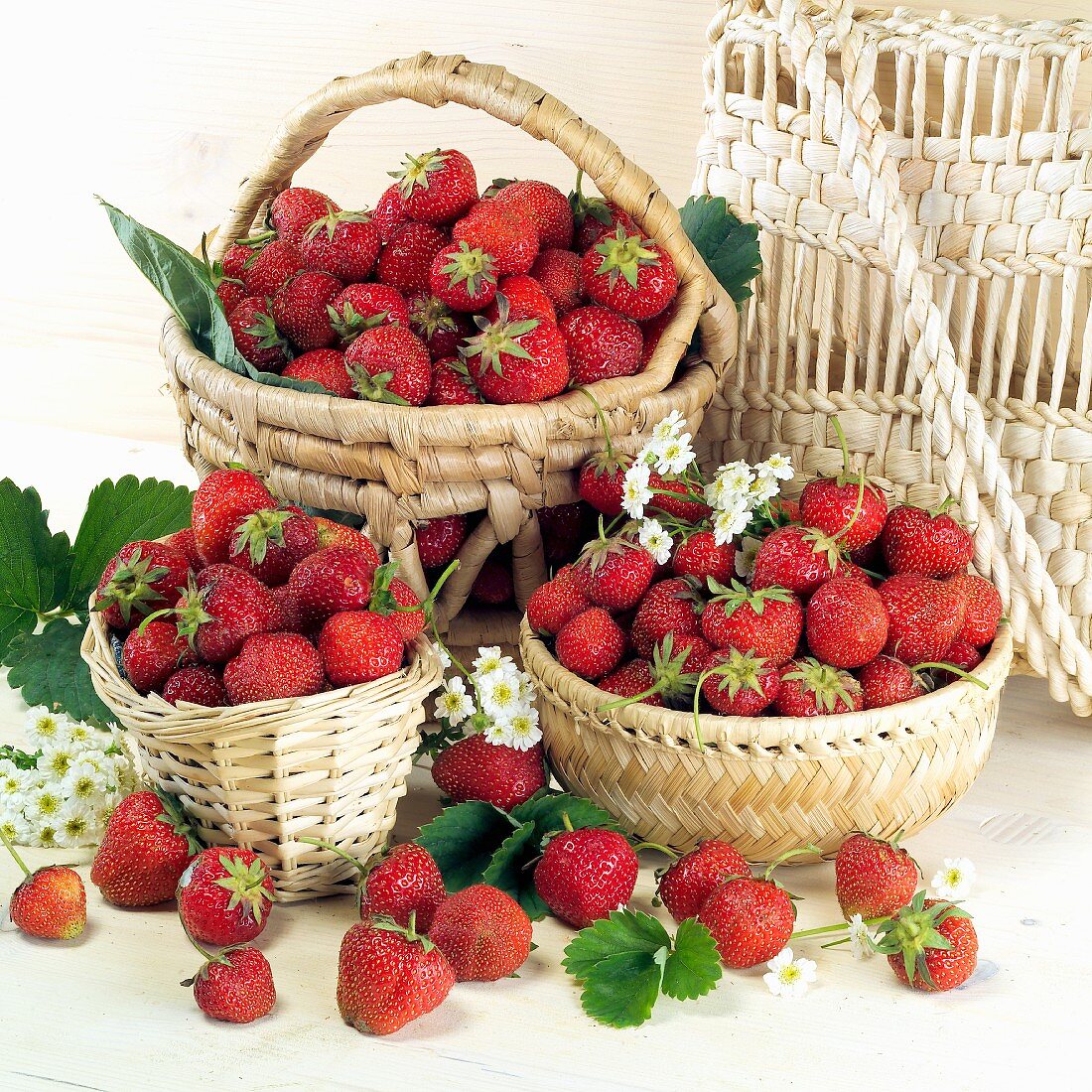 Fresh strawberries in and in front of three baskets