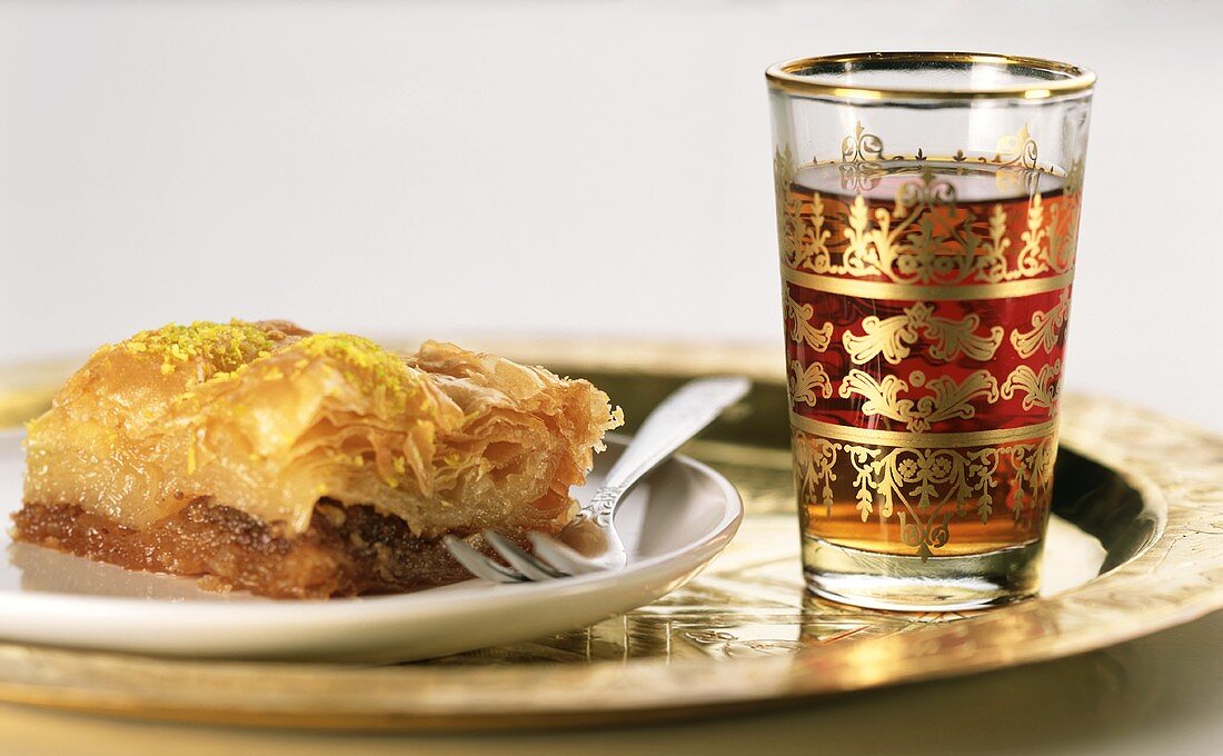 Piece of baklava on a plate and glass of tea
