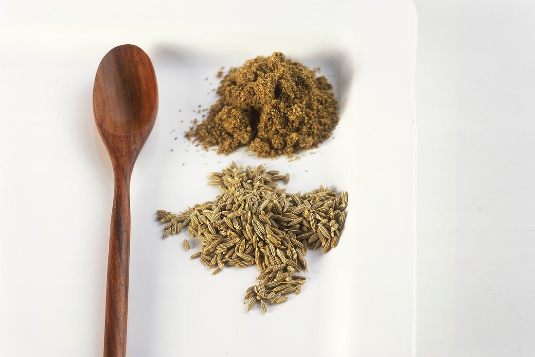 Cumin, ground and unground with wooden spoon