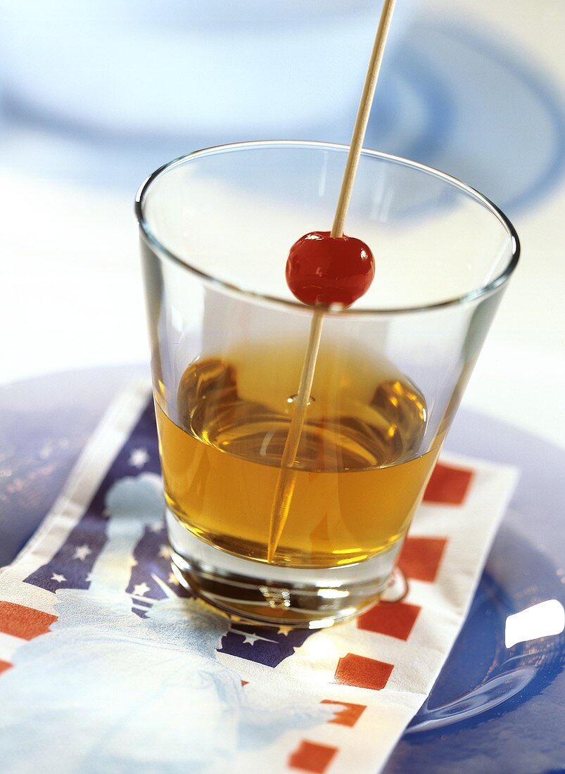 Manhattan im Whiskeyglas, Spiess mit Cocktailkirsche