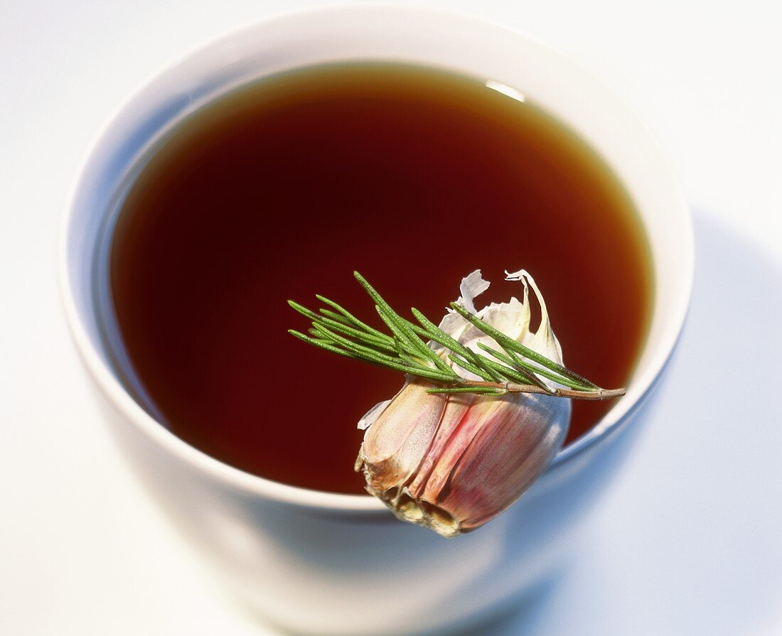 Game stock in a bowl with garlic and rosemary