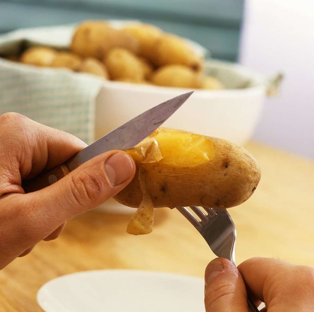 Peeling boiled potato (pulling off the skin)