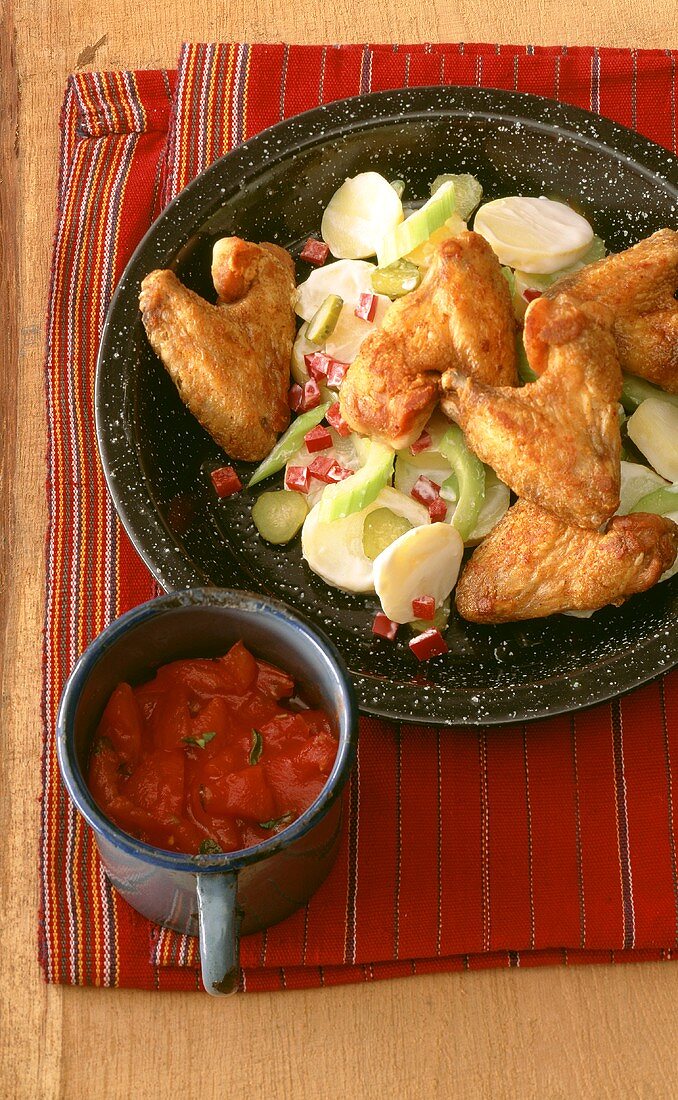 Chicken Wings auf Kartoffelsalat und Becher Tomatensauce