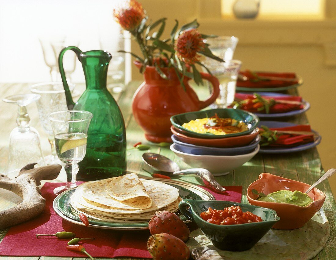 Party table with tortillas and toppings (fillings, sauces)
