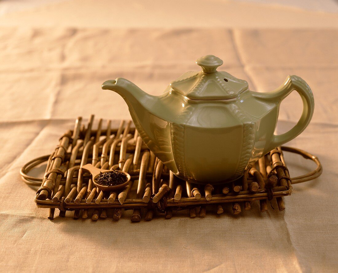 Teemasslöffel mit Schwarzteemischung und eine Teekanne