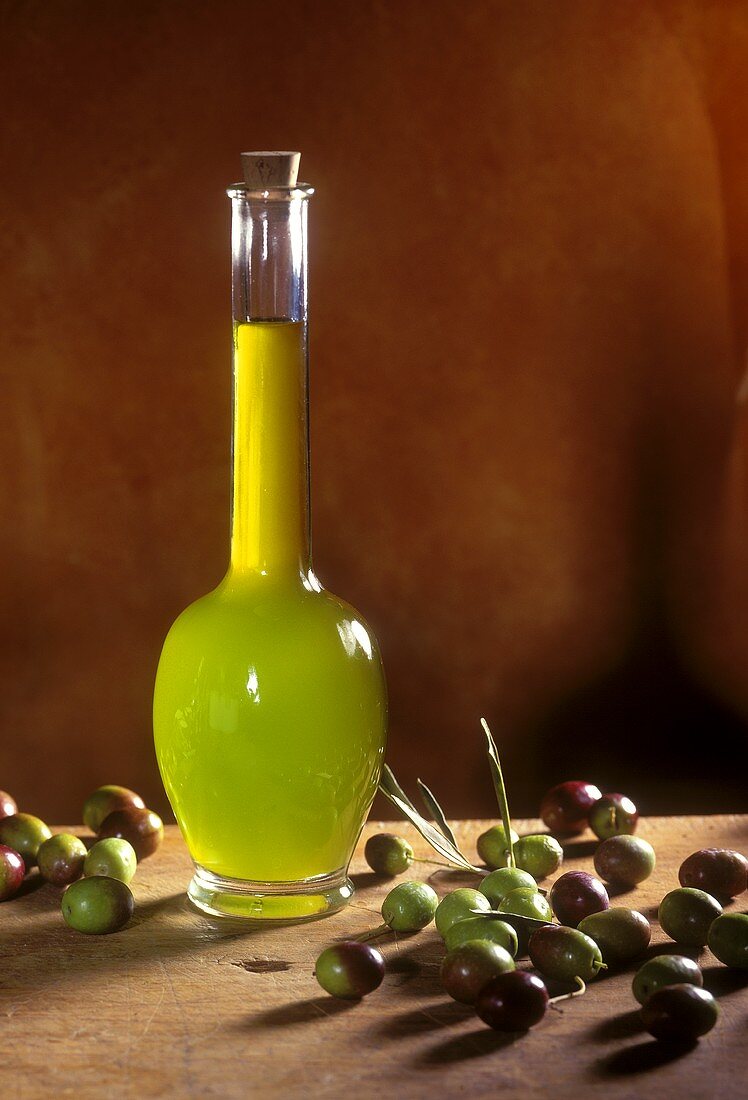 Olive oil in a bulbous glass bottle with olives